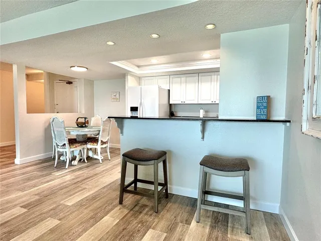 a kitchen with stainless steel appliances kitchen island granite countertop a dining table chairs and a refrigerator