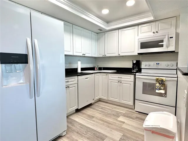 a kitchen with stainless steel appliances granite countertop a refrigerator sink and white cabinets