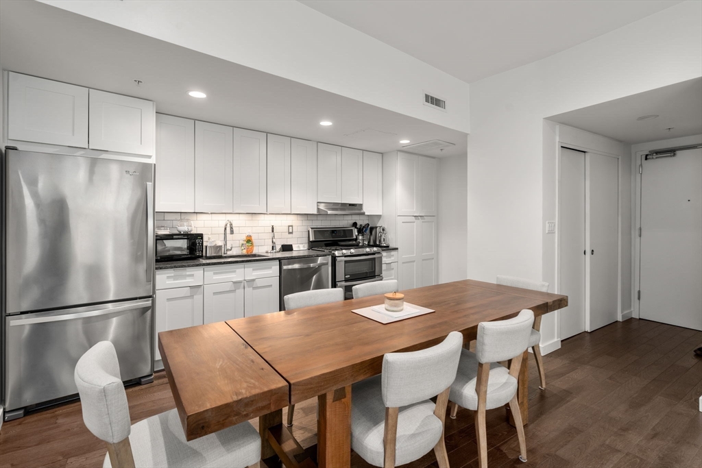 126 Salem Street, Unit 3 Boston, MA 02113 - Photo 5 of 27 a kitchen with stainless steel appliances granite countertop a dining table chairs refrigerator and cabinets