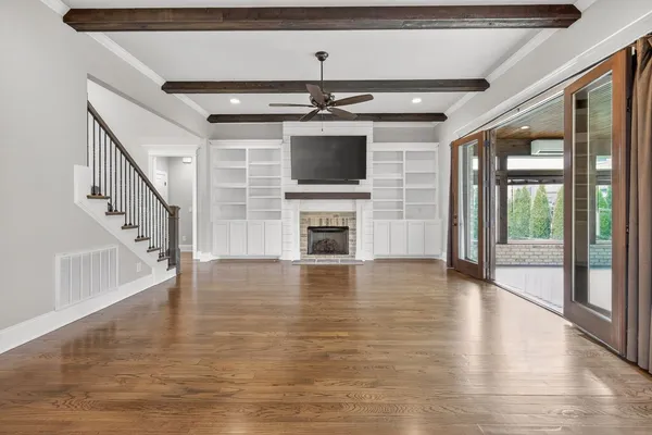 a view of a livingroom with wooden floor a ceiling fan and windows