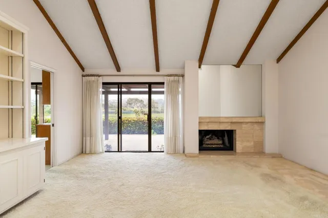 a view of an empty room with fireplace and a window