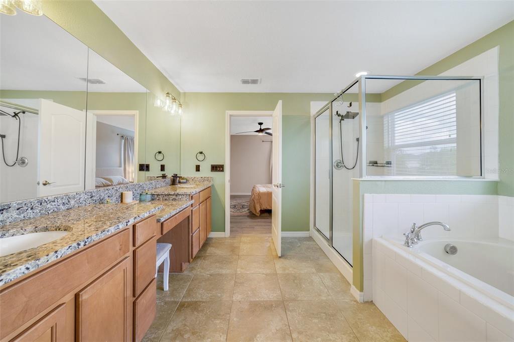 1354 Riley Circle DeLand, FL 32724 - Photo 10 of 22 The en suite primary bathroom offers dual sinks, a dedicated makeup area, a glass-enclosed shower, and a generous soaking tub, creating a spa-like retreat right at home.