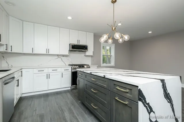 a kitchen with a stove a sink and a chandelier