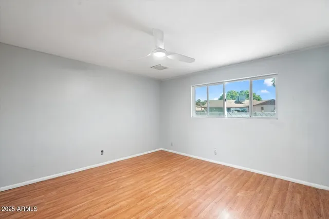 an empty room with window and ceiling fan