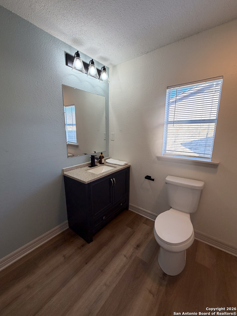 409 Coughran Street Pleasanton, TX 78064 - Photo 6 of 16 a bathroom with a toilet sink a mirror and vanity