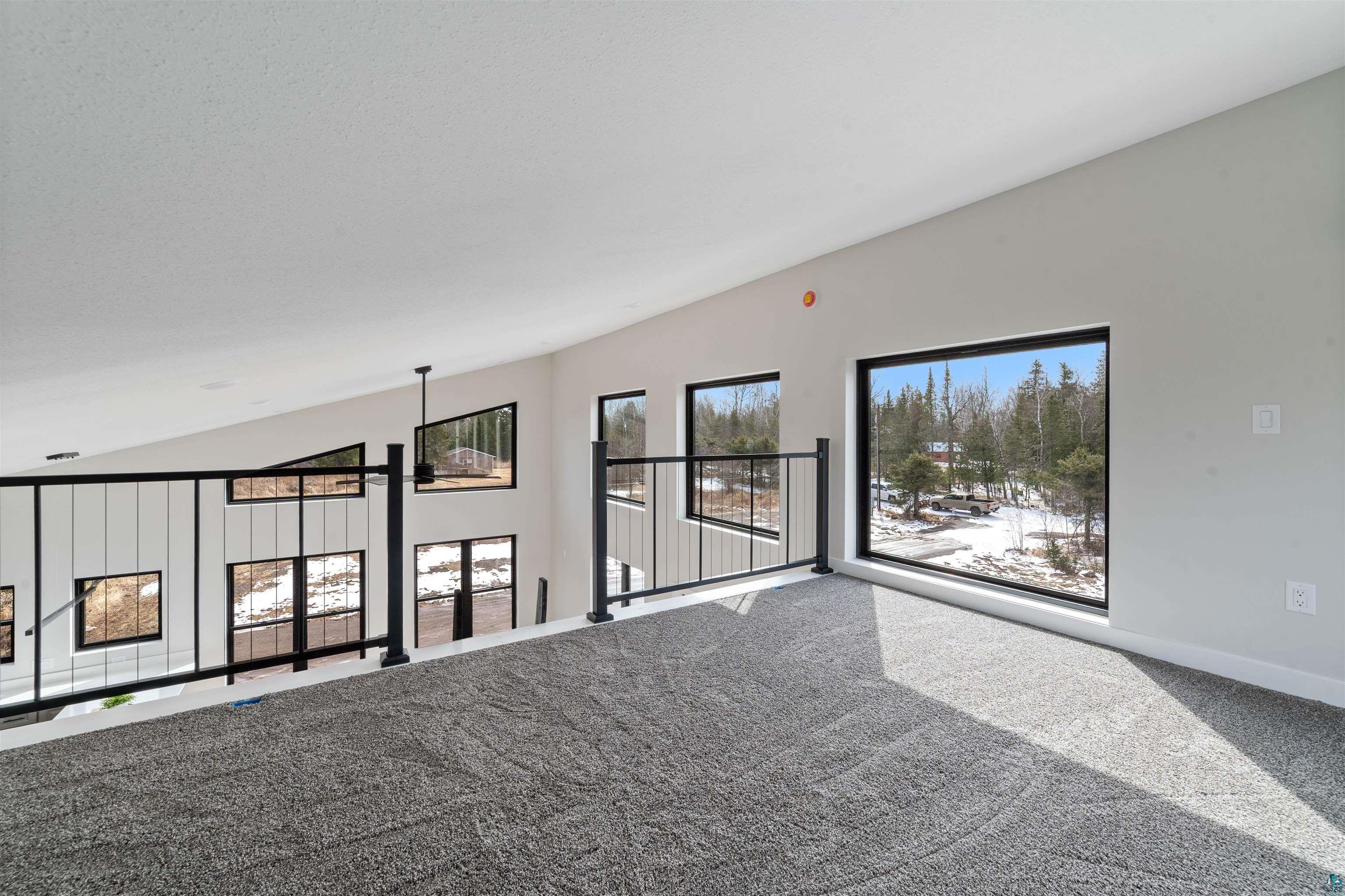 3089 Lavis Road Duluth, MN 55804 - Photo 11 of 30 Carpeted empty room with baseboards, lofted ceiling, and a healthy amount of sunlight