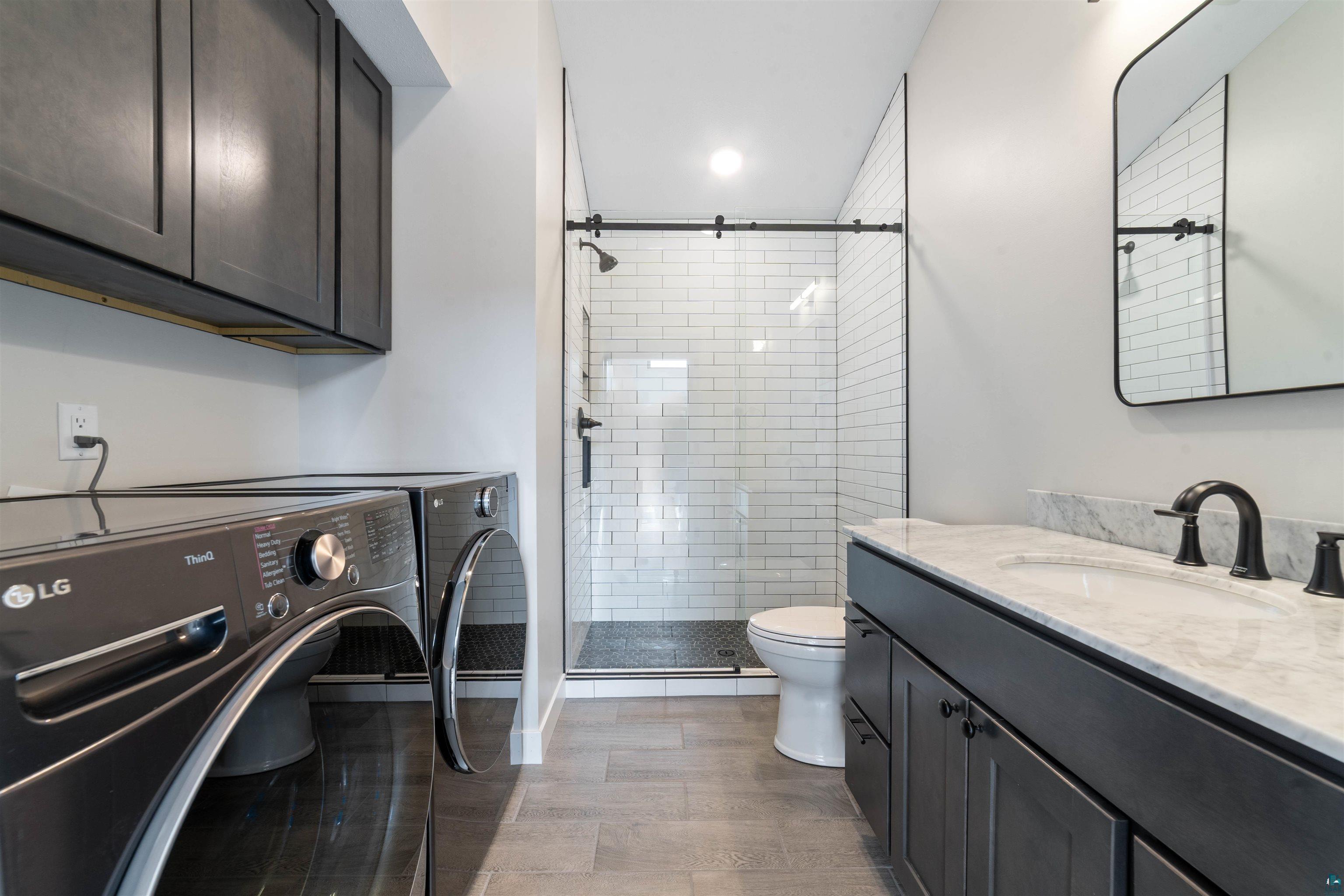 3089 Lavis Road Duluth, MN 55804 - Photo 21 of 30 Bathroom with washing machine and clothes dryer, toilet, a stall shower, and vanity