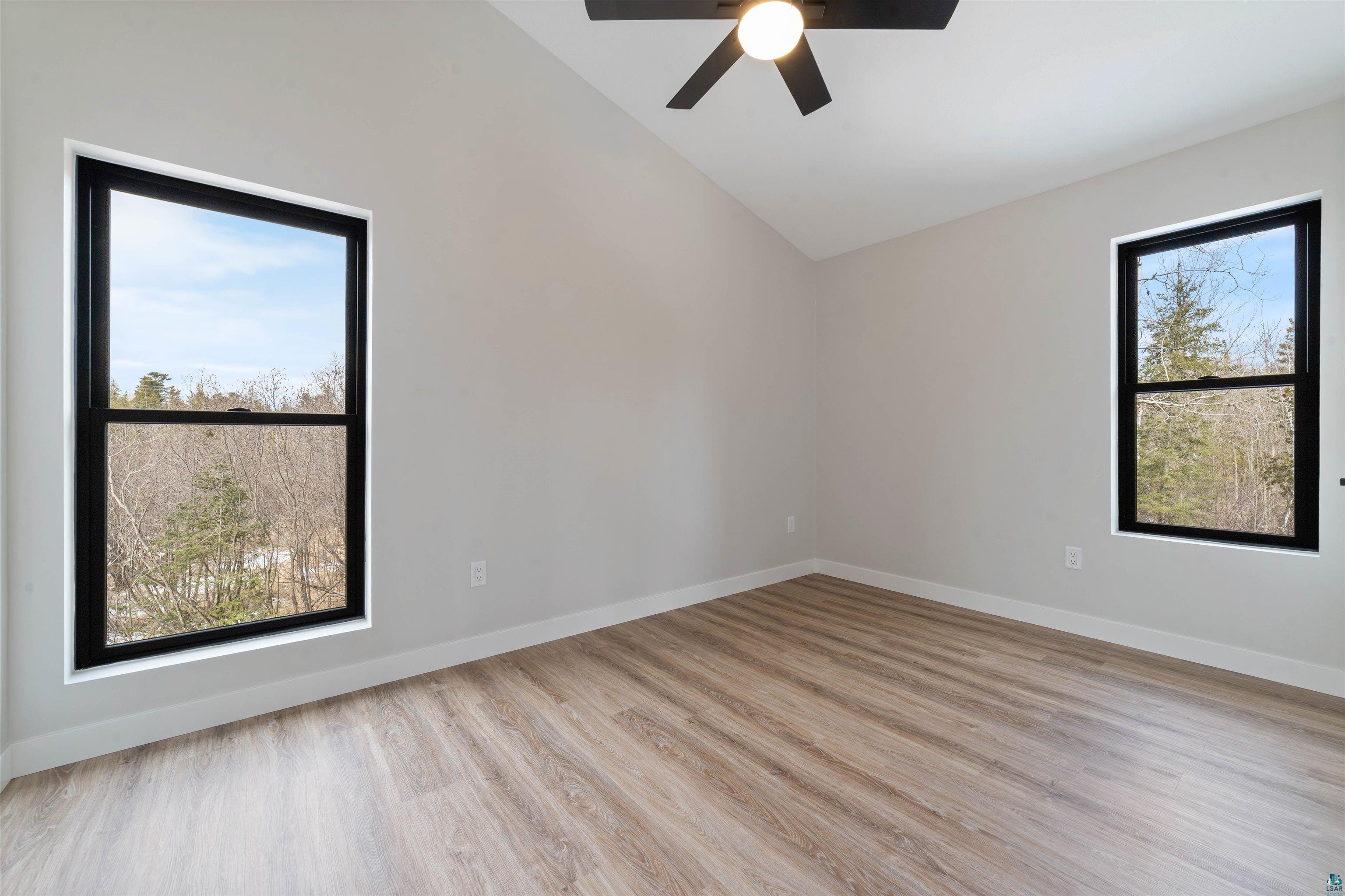 3089 Lavis Road Duluth, MN 55804 - Photo 22 of 30 Empty room featuring baseboards, ceiling fan, wood finished floors, and vaulted ceiling