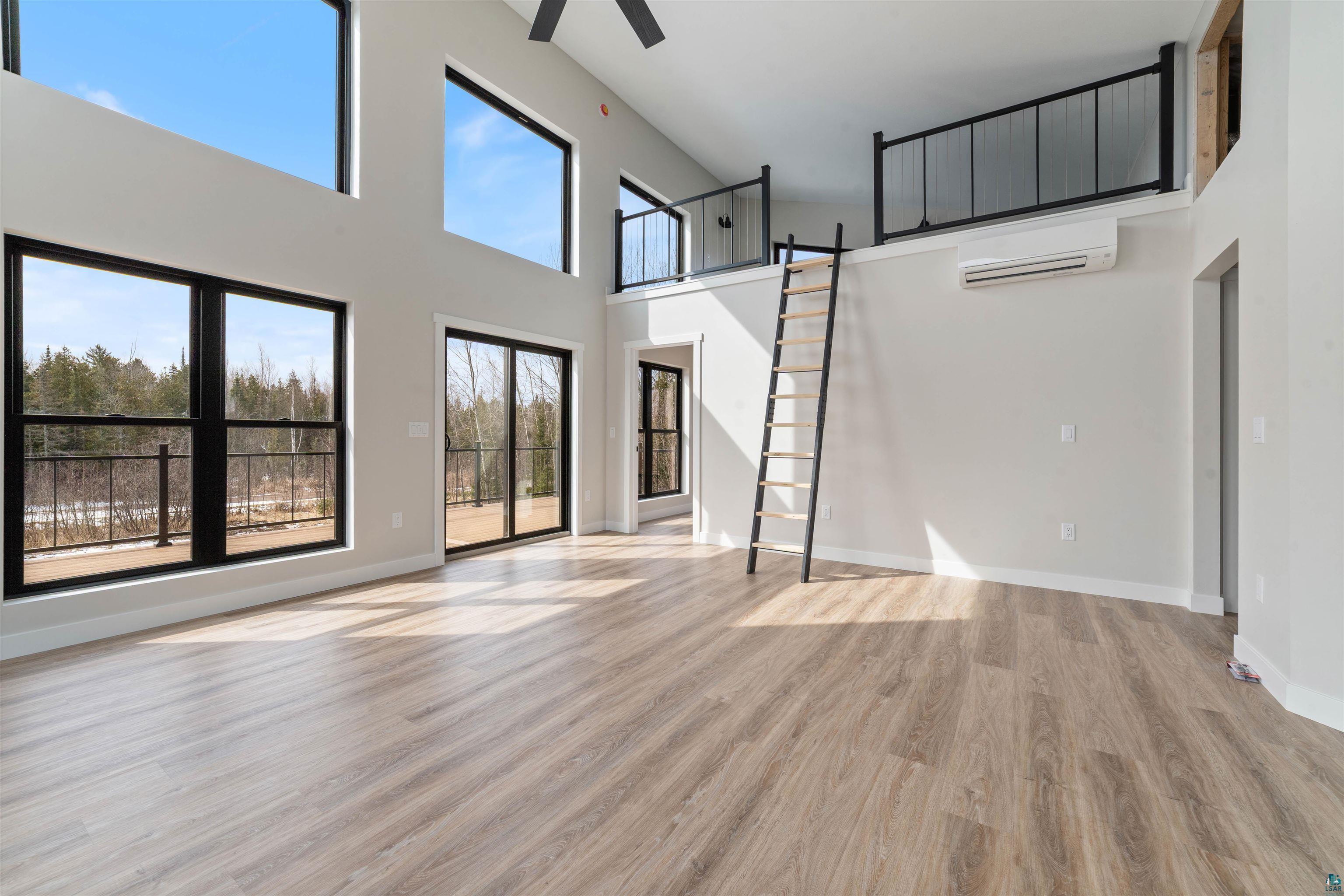 3089 Lavis Road Duluth, MN 55804 - Photo 6 of 30 Unfurnished living room featuring a ceiling fan, a wall unit AC, baseboards, and light wood finished floors