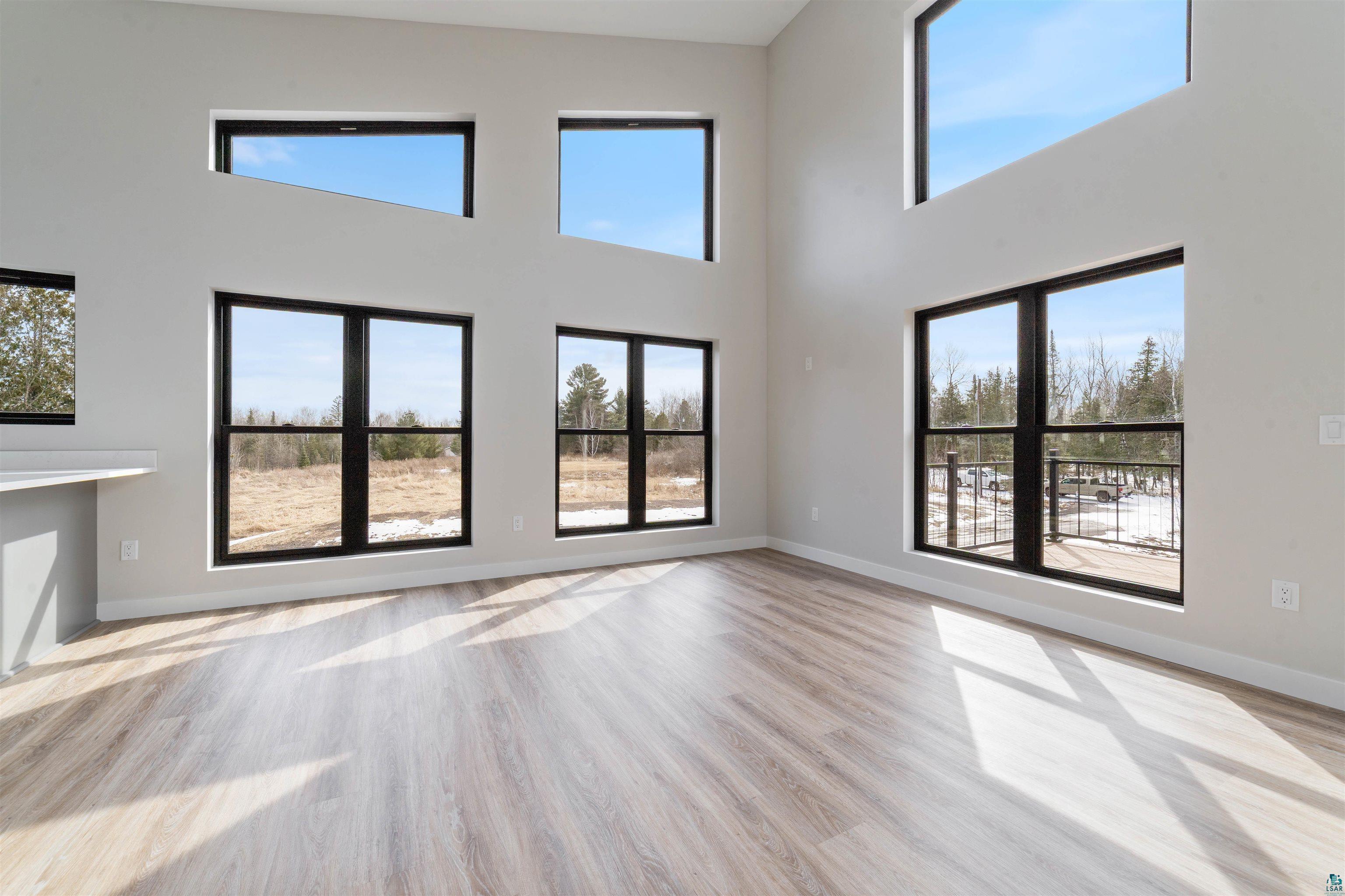 3089 Lavis Road Duluth, MN 55804 - Photo 7 of 30 Unfurnished living room with baseboards, a high ceiling, and wood finished floors