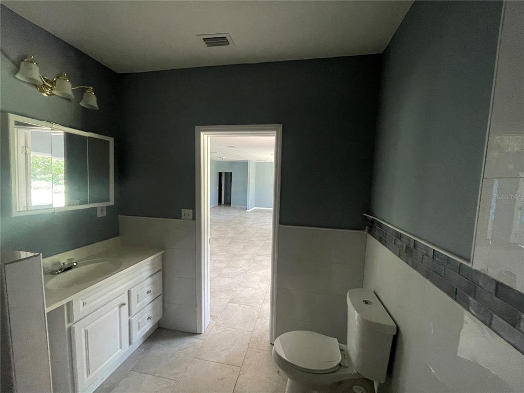 8704 Jackson Springs Road Tampa, FL 33615 - Photo 13 of 21 a bathroom with a granite countertop sink toilet and mirror