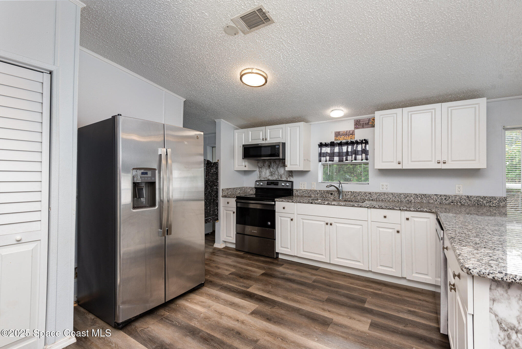 3115 Brockett Road Mims, FL 32754 - Photo 6 of 15 a kitchen with granite countertop a refrigerator stove and microwave
