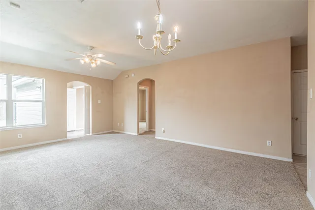 an empty room with chandelier fan and windows