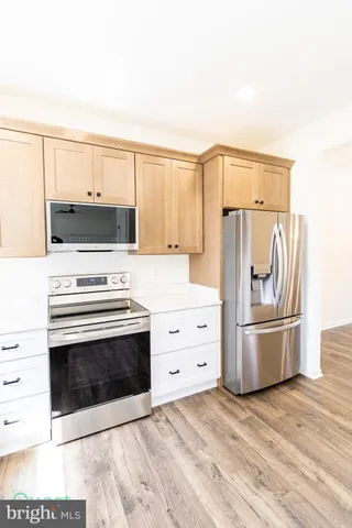a large white kitchen with stainless steel appliances kitchen island a stove a sink dishwasher and a refrigerator