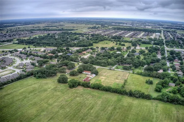 an aerial view of residential houses with outdoor space and trees