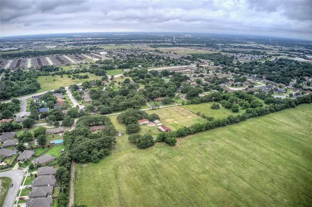 an aerial view of residential houses with outdoor space and trees