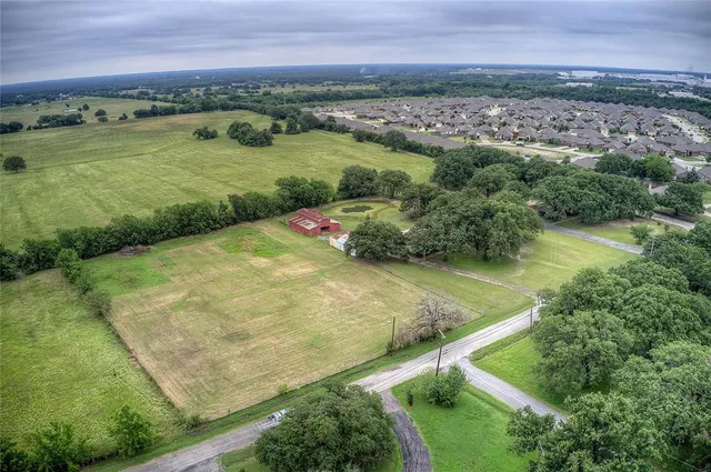 an aerial view of residential houses with outdoor space and trees