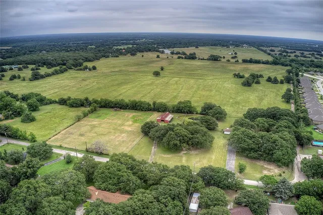 an aerial view of residential houses with outdoor space and trees