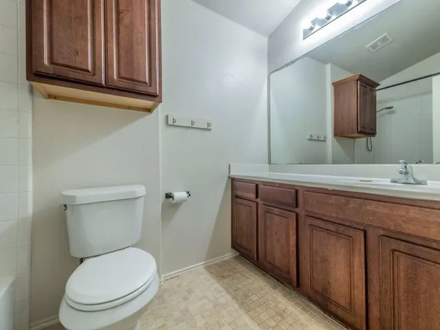 a bathroom with a granite countertop toilet sink and mirror