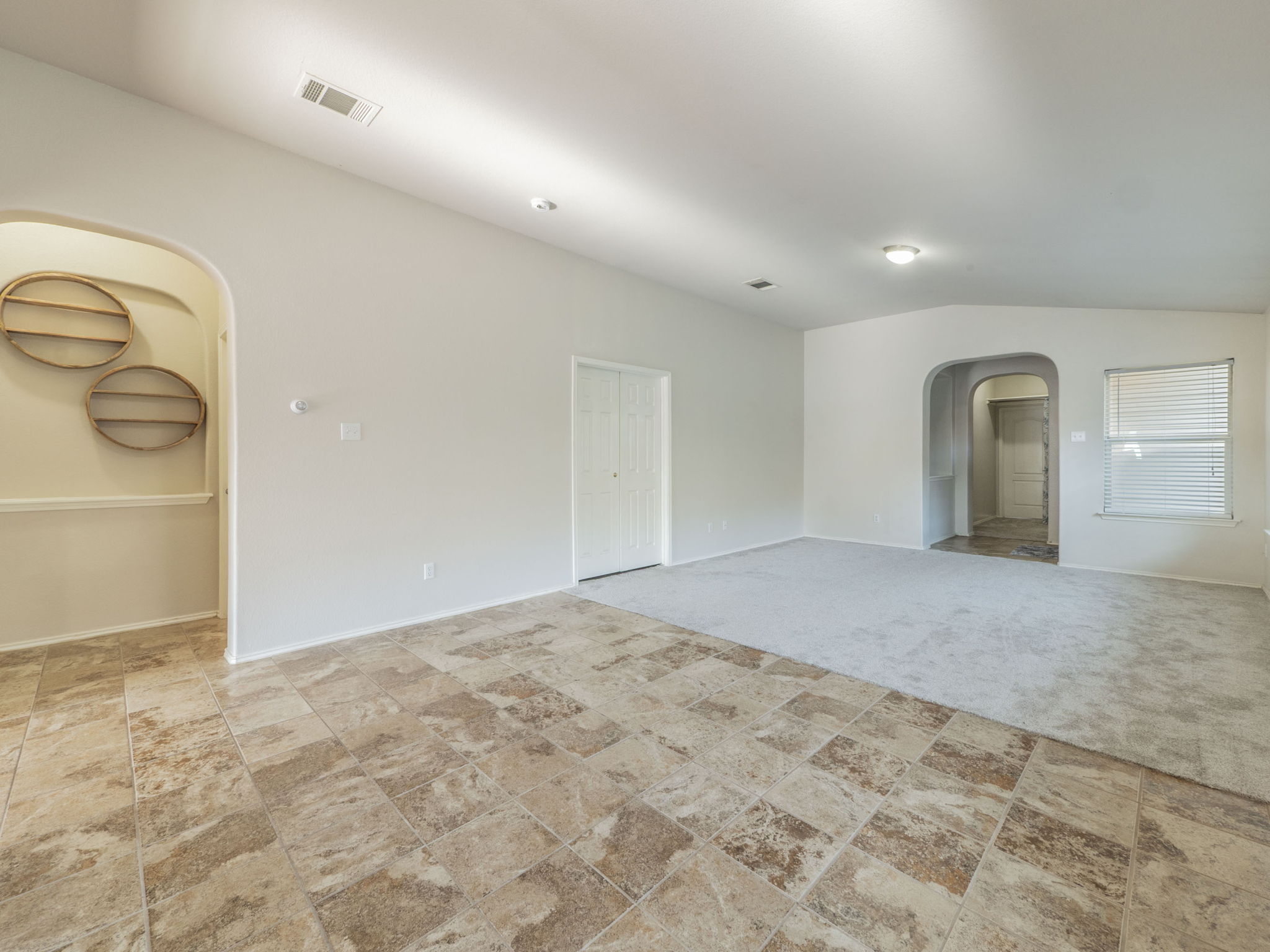 3209 Wickham Lane Austin, TX 78725 - Photo 5 of 26 Empty room with arched walkways, lofted ceiling, and light colored carpet