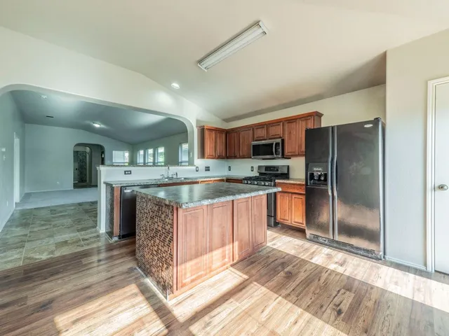 a kitchen with stainless steel appliances granite countertop a refrigerator and a stove top oven