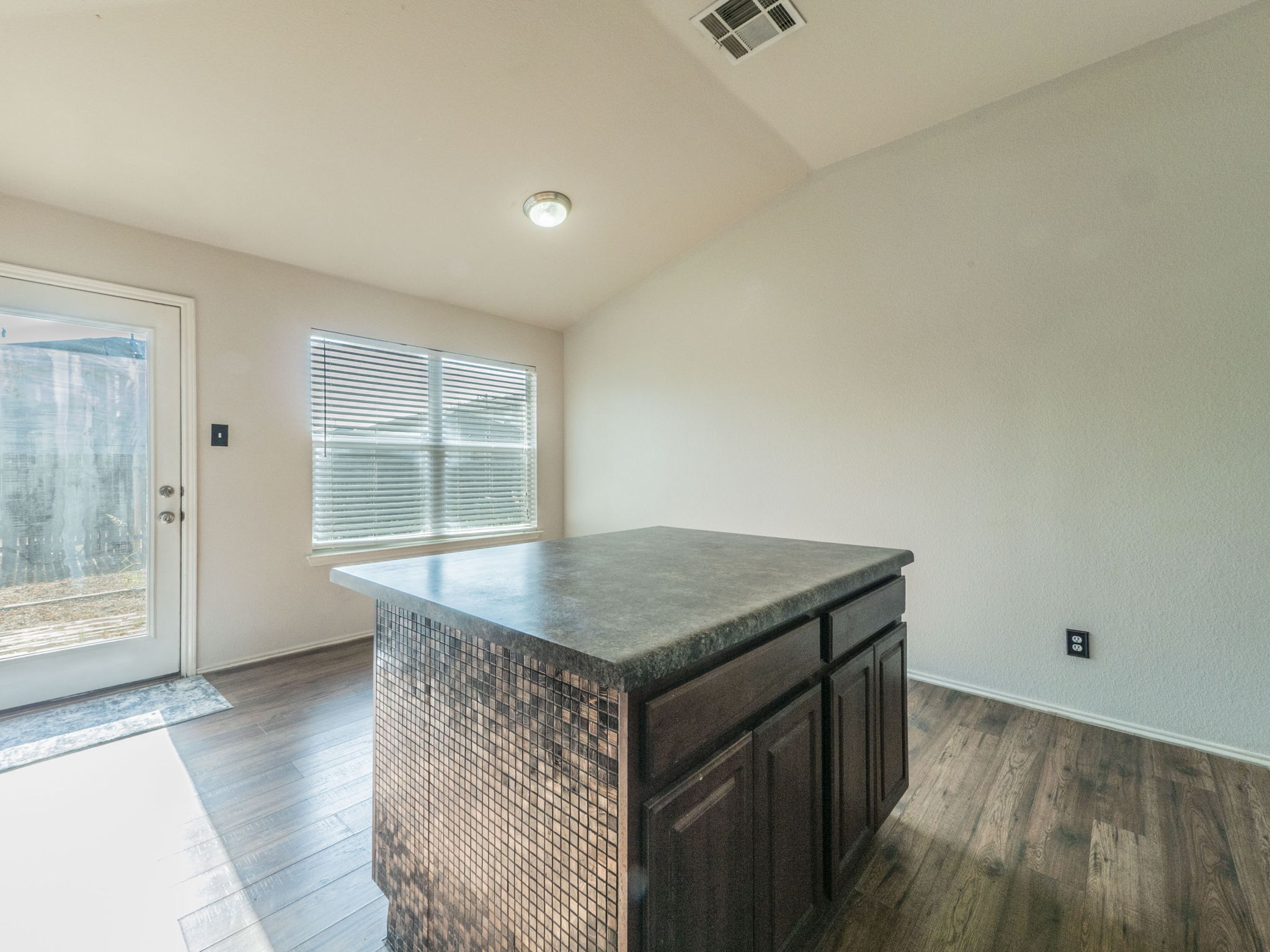 3209 Wickham Lane Austin, TX 78725 - Photo 8 of 26 Kitchen with vaulted ceiling, dark countertops, dark brown cabinets, dark wood-style floors, and a center island