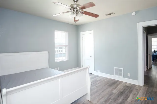 a view of an empty room with window and wooden floor