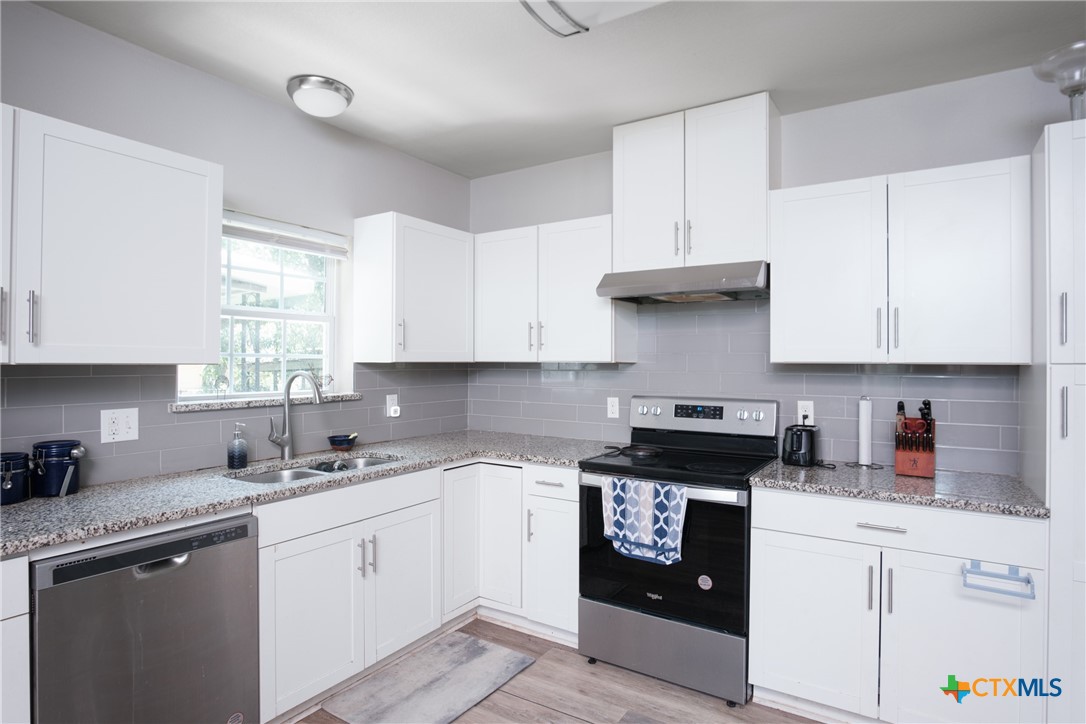 921 South 11th Street Temple, TX 76504 - Photo 10 of 23 a kitchen with granite countertop white cabinets white stainless steel appliances and sink