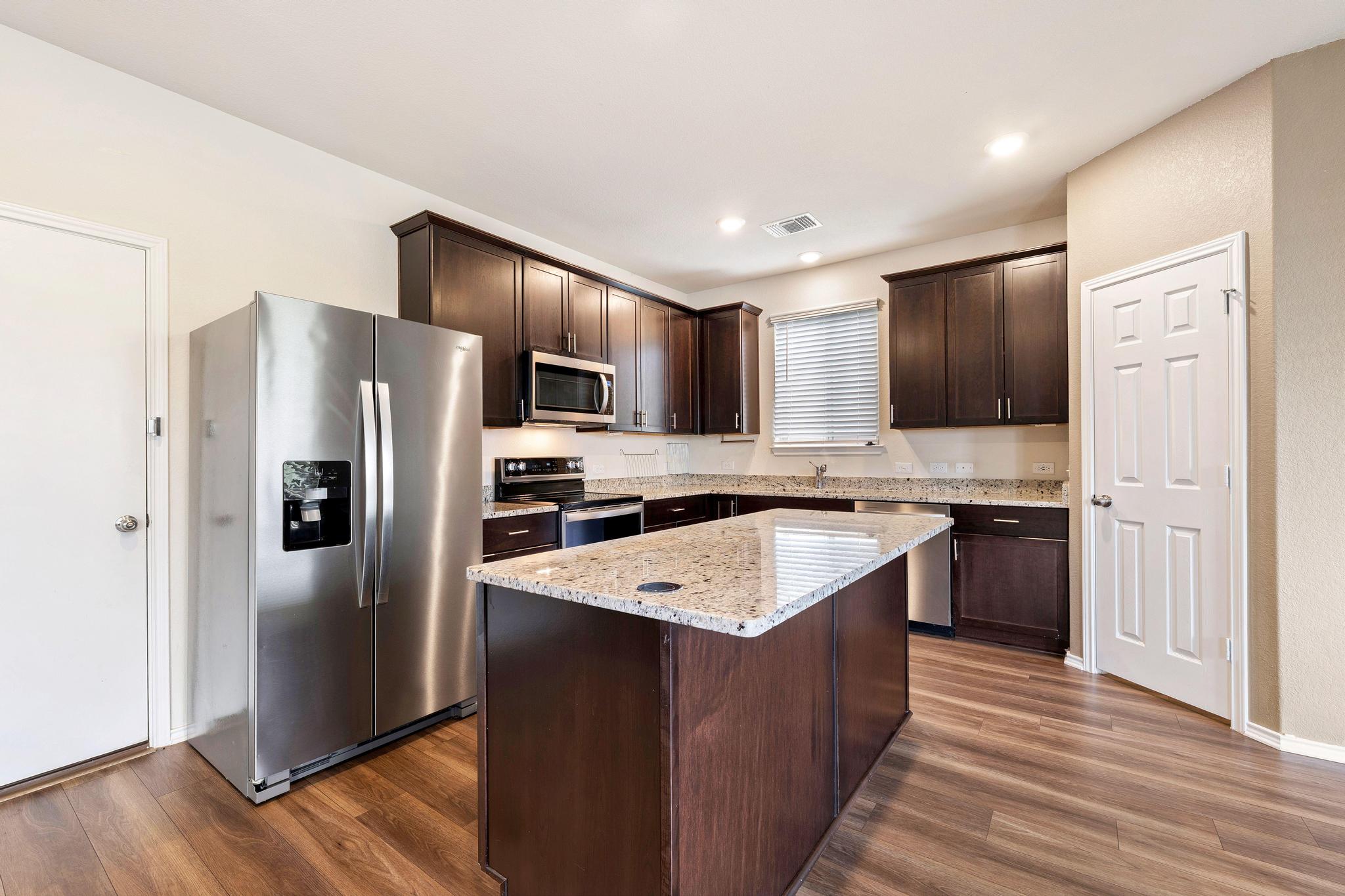 217 Innisfree Road Jarrell, TX 76537 - Photo 12 of 39 Culinary creations come to life in this modern kitchen, featuring an inviting island and elegant granite countertops.