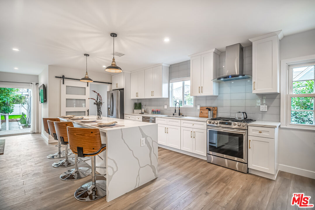 5619 Bellingham Avenue Valley Village, CA 91607 - Photo 9 of 48 a kitchen with kitchen island stainless steel appliances a dining table and chairs