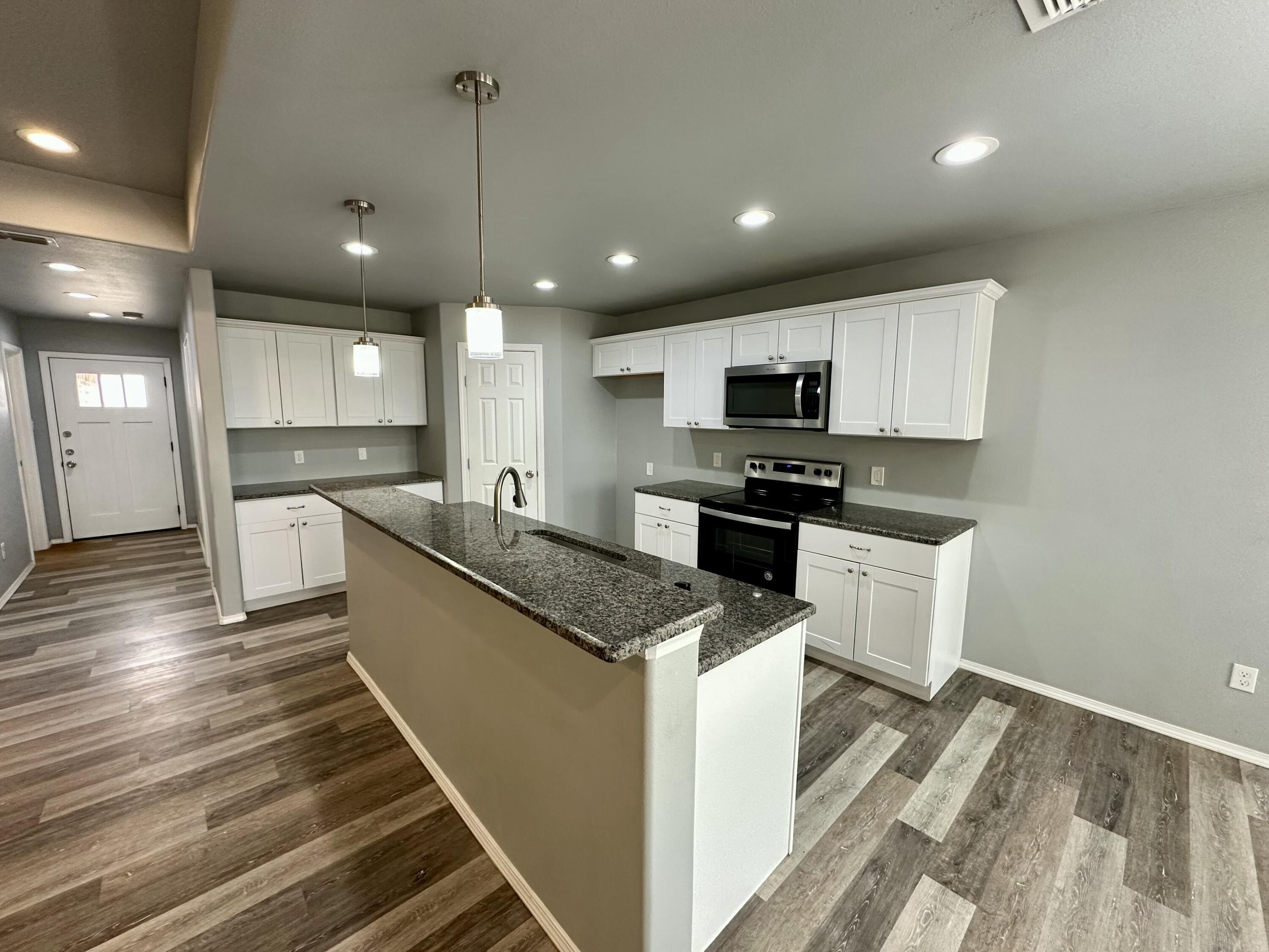 8434 11th Street Lubbock, TX 79416 - Photo 3 of 11 a large kitchen with granite countertop a large counter top stainless steel appliances and cabinets