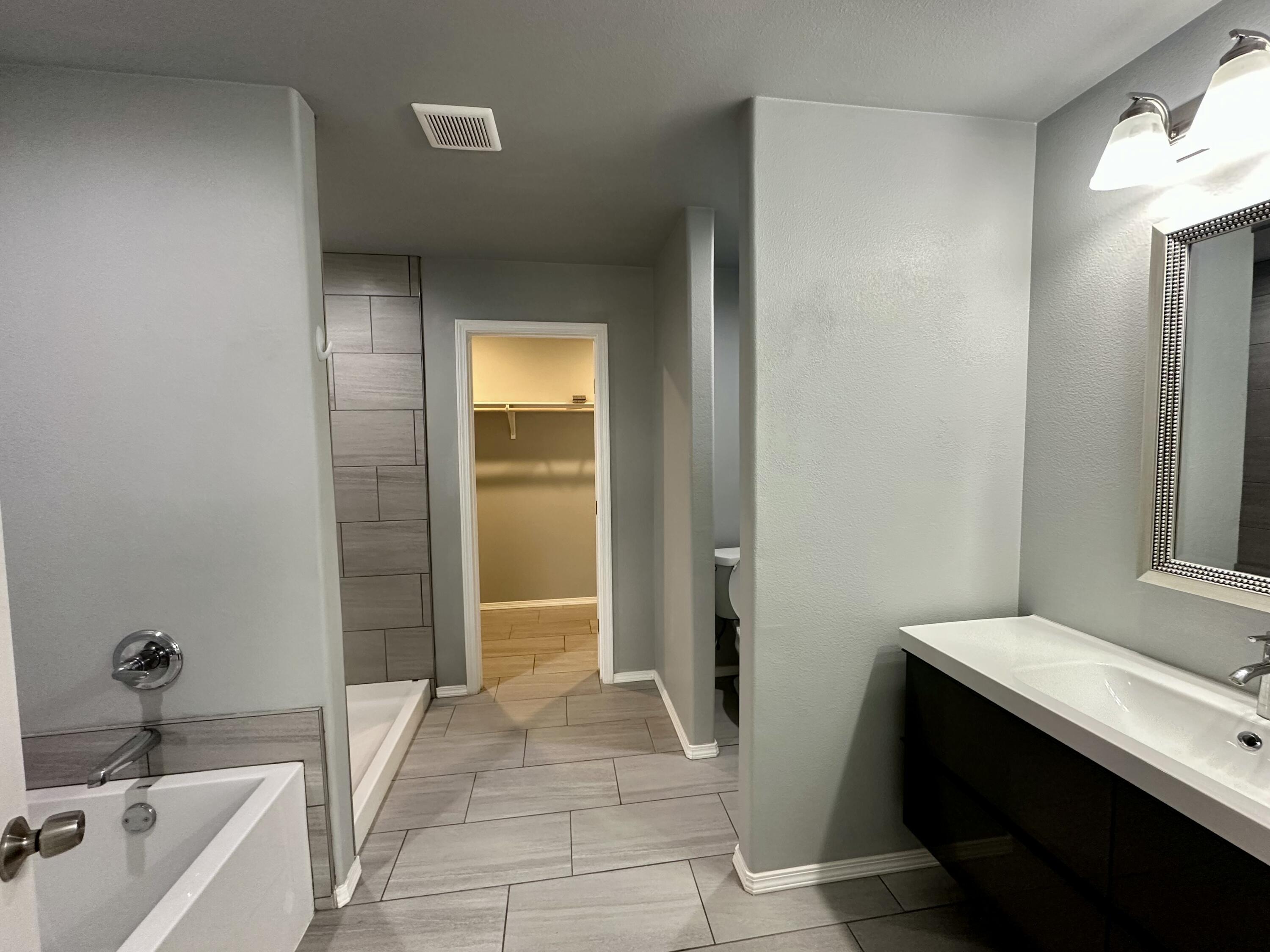 8434 11th Street Lubbock, TX 79416 - Photo 6 of 11 a bathroom with a tub sink and mirror