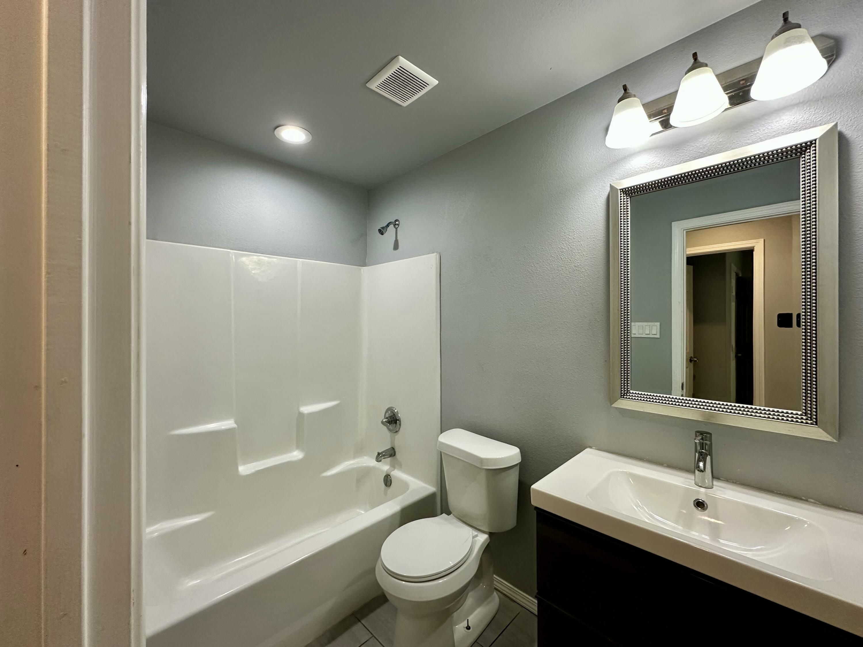 8434 11th Street Lubbock, TX 79416 - Photo 9 of 11 a bathroom with a sink a toilet and shower