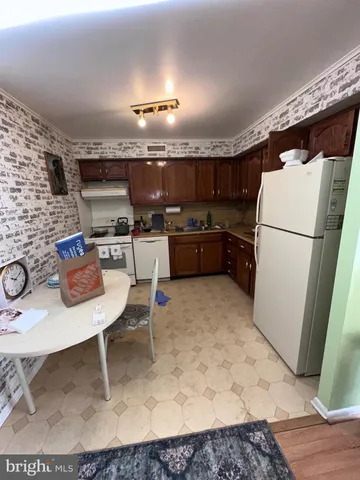 a kitchen with a refrigerator a stove a sink dishwasher with a dining table and chair