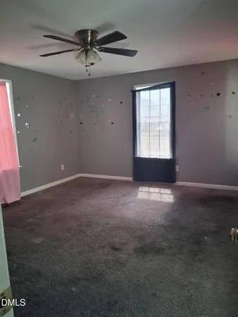 an empty room with a ceiling fan and window