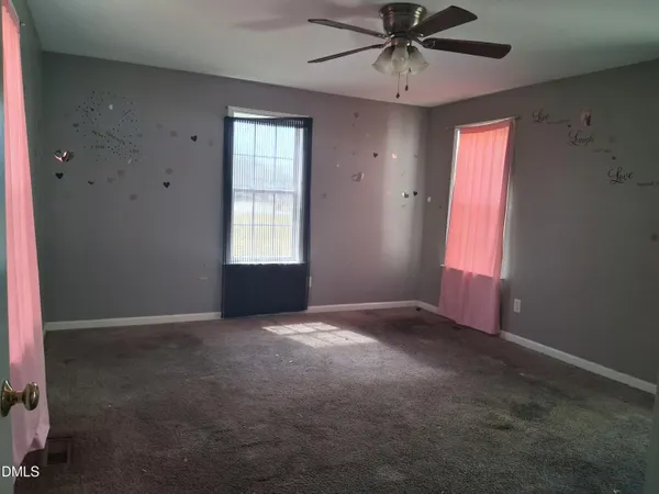 an empty room with windows and fan