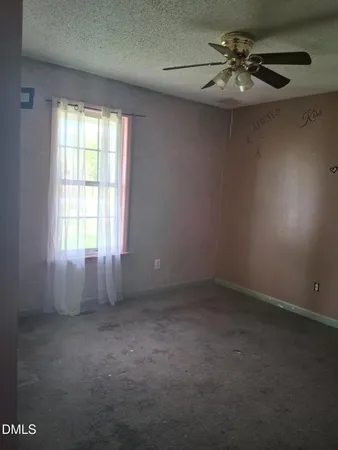 an empty room with a chandelier fan and windows