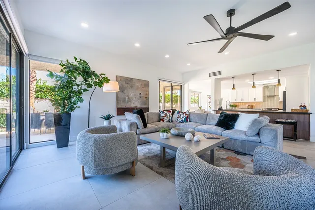a living room with furniture kitchen view and a large window