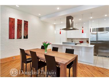 169 Spring Street, Unit 6 Manhattan, NY 10012 - Photo 1 of 1 a kitchen with stainless steel appliances kitchen island granite countertop a table chairs and a refrigerator