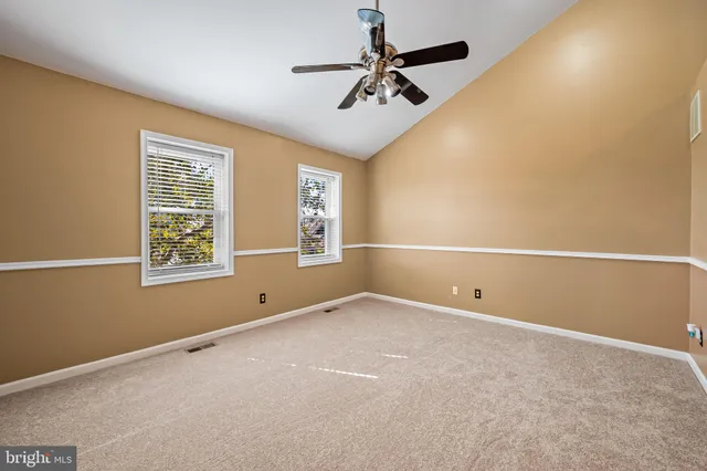an empty room with windows and ceiling fan