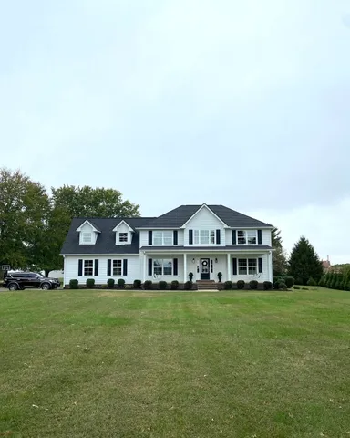 a front view of a house with a big yard and large trees