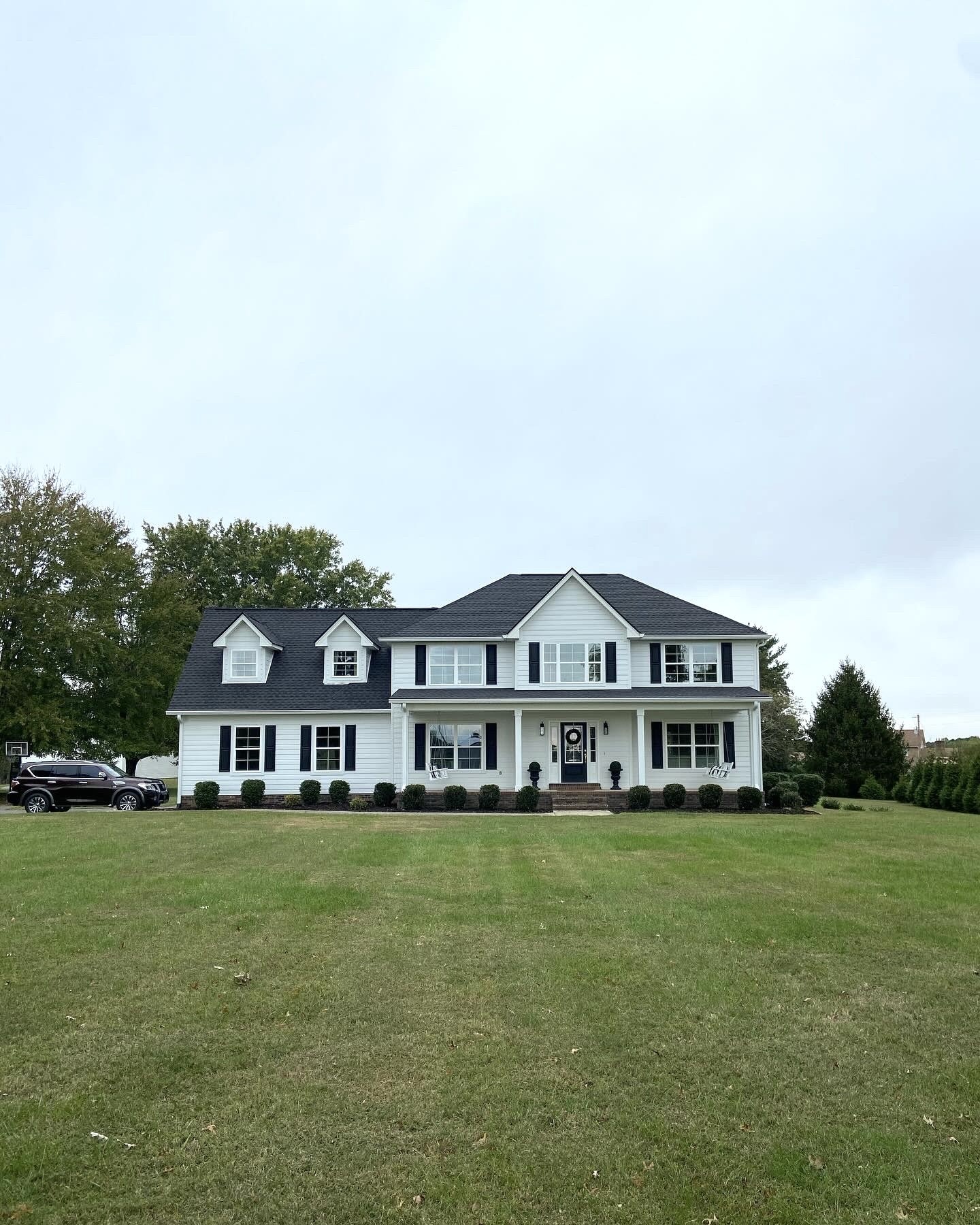 a front view of a house with a big yard and large trees