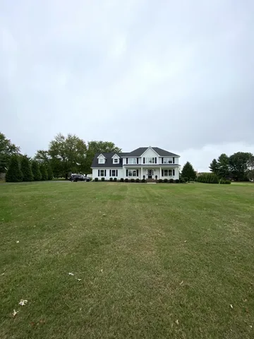 a front view of a house with a garden and trees