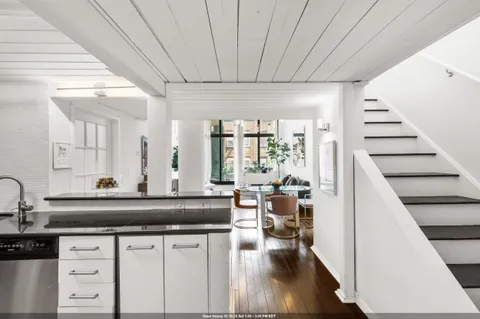 a living room with furniture a large window and wooden floor