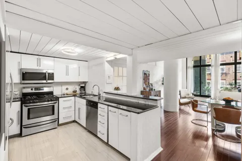 a kitchen with stainless steel appliances a refrigerator a sink a stove top oven a counter space and cabinets