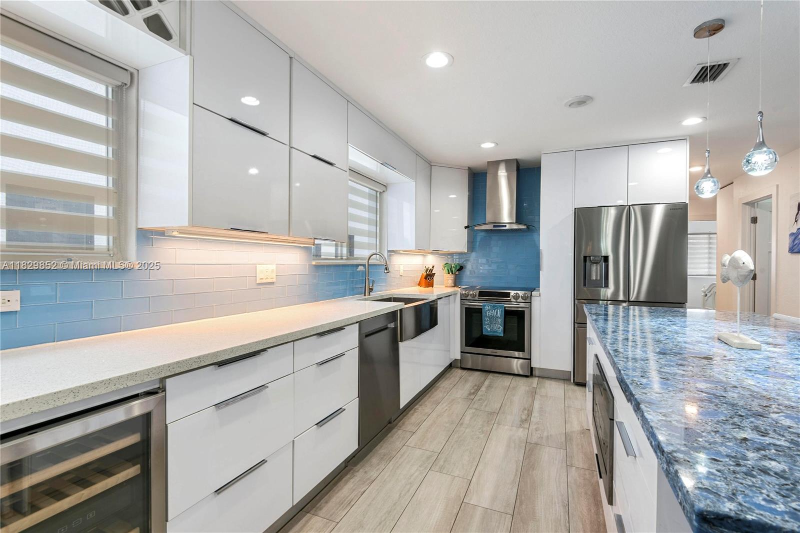 325 Calusa Street Key Largo, FL 33037 - Photo 5 of 17 a large kitchen with a center island wooden floor stainless steel appliances and windows