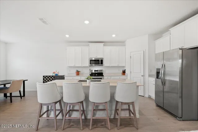 a kitchen with stainless steel appliances a table chairs refrigerator and a sink