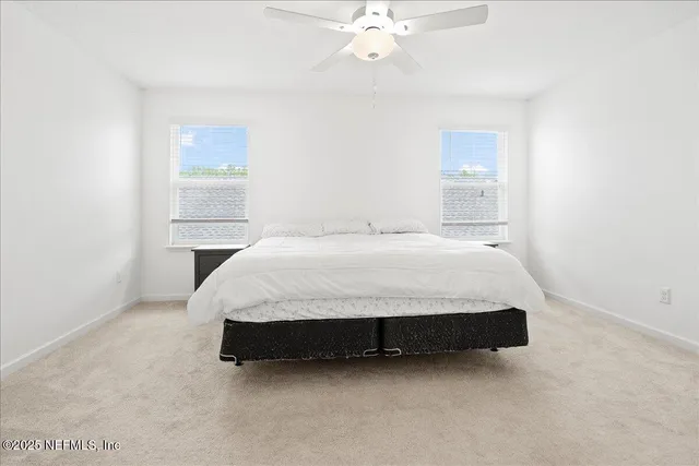 a bed sitting in a bedroom next to a window and a chandelier