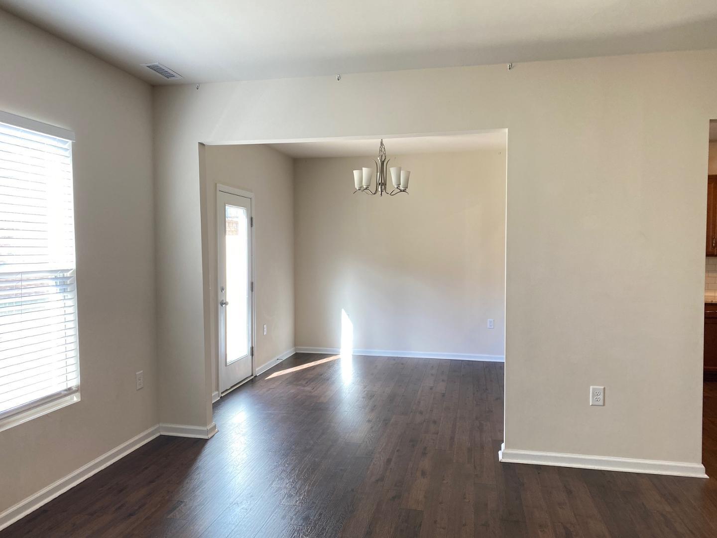 1005 Saffron Loop Durham, NC 27713 - Photo 5 of 26 an empty room with wooden floor and windows with curtains