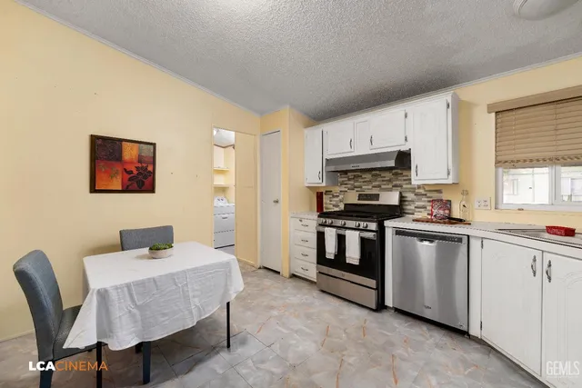 a kitchen with stainless steel appliances kitchen island granite countertop a stove top oven a sink a dining table and chairs